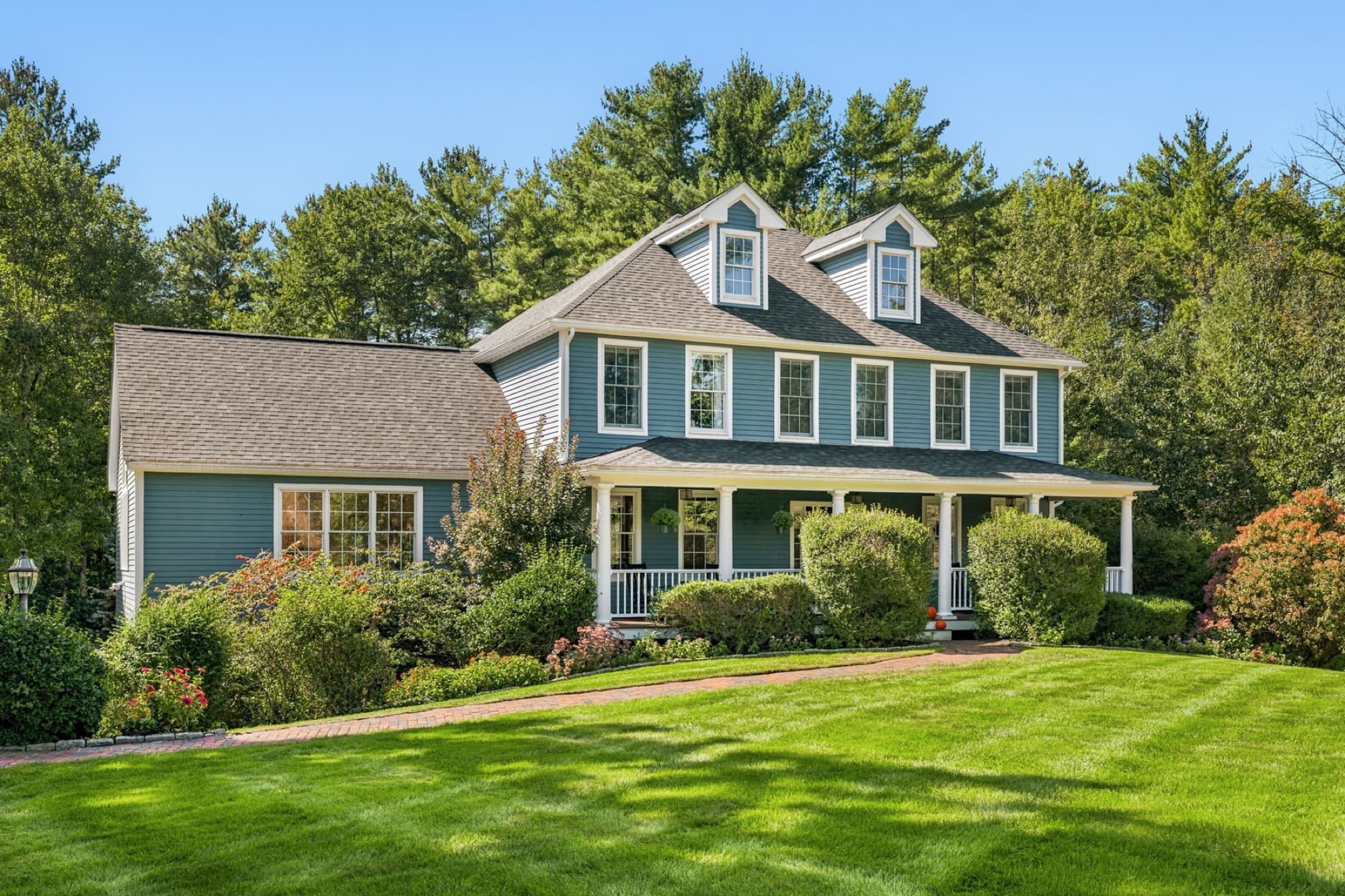 The blue Colonial from the front lawn, with the farmer's porch, 3 dormers, and the garage wing to the left