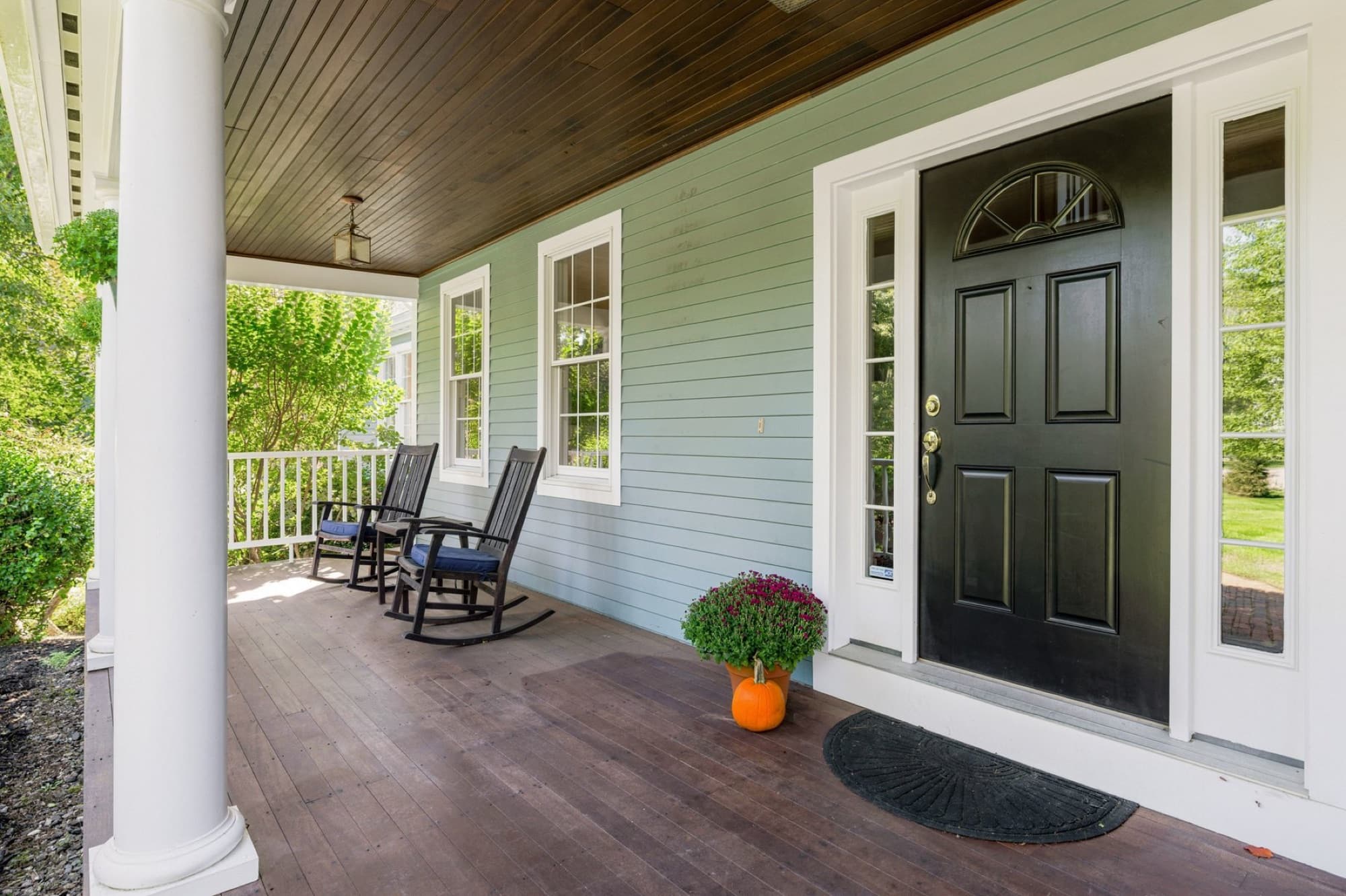 The farmer's porch with 2 rocking chairs, the black front door, and a bead-board ceiling