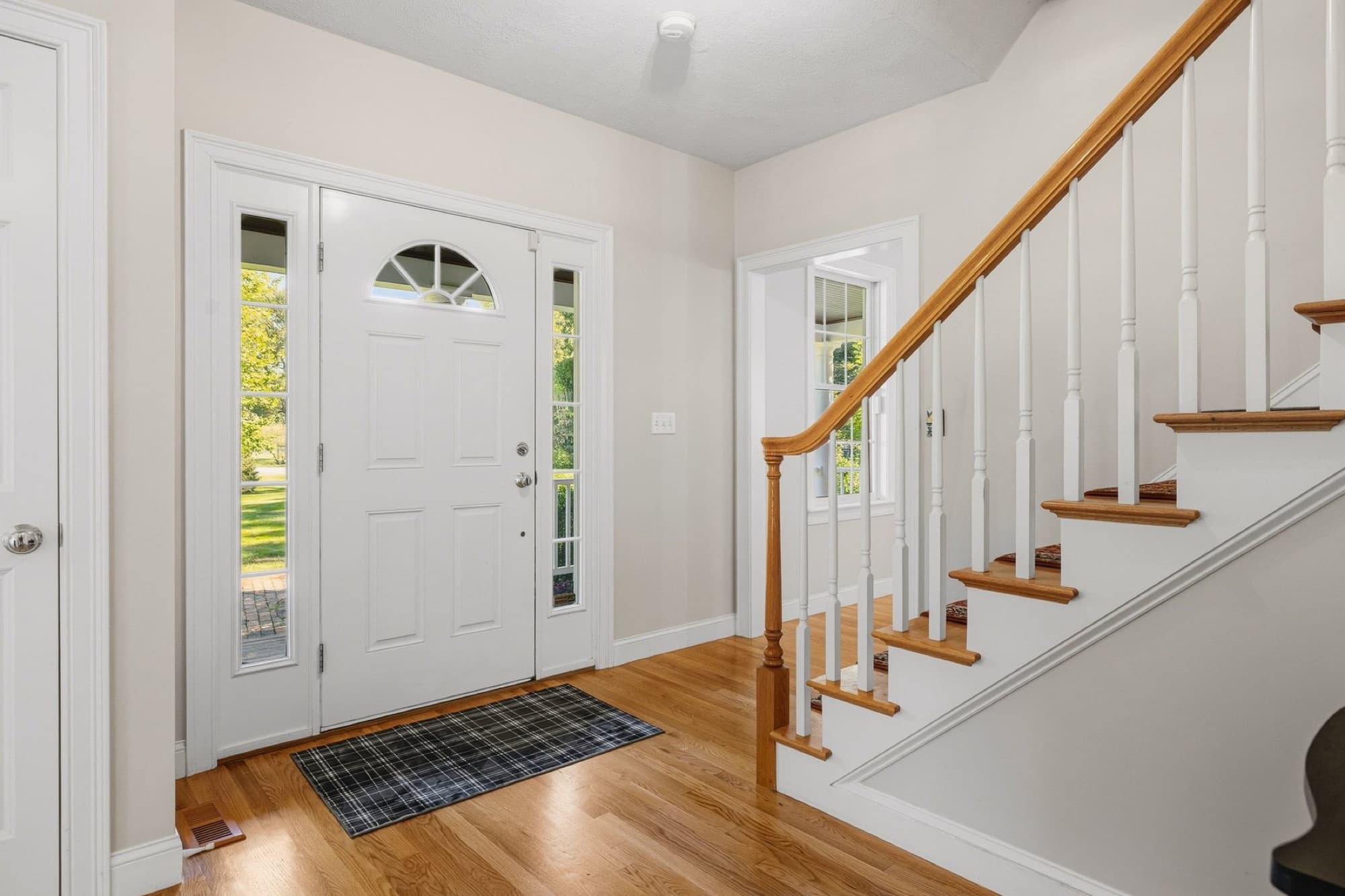 The foyer with the front door, its sidelights, and the staircase