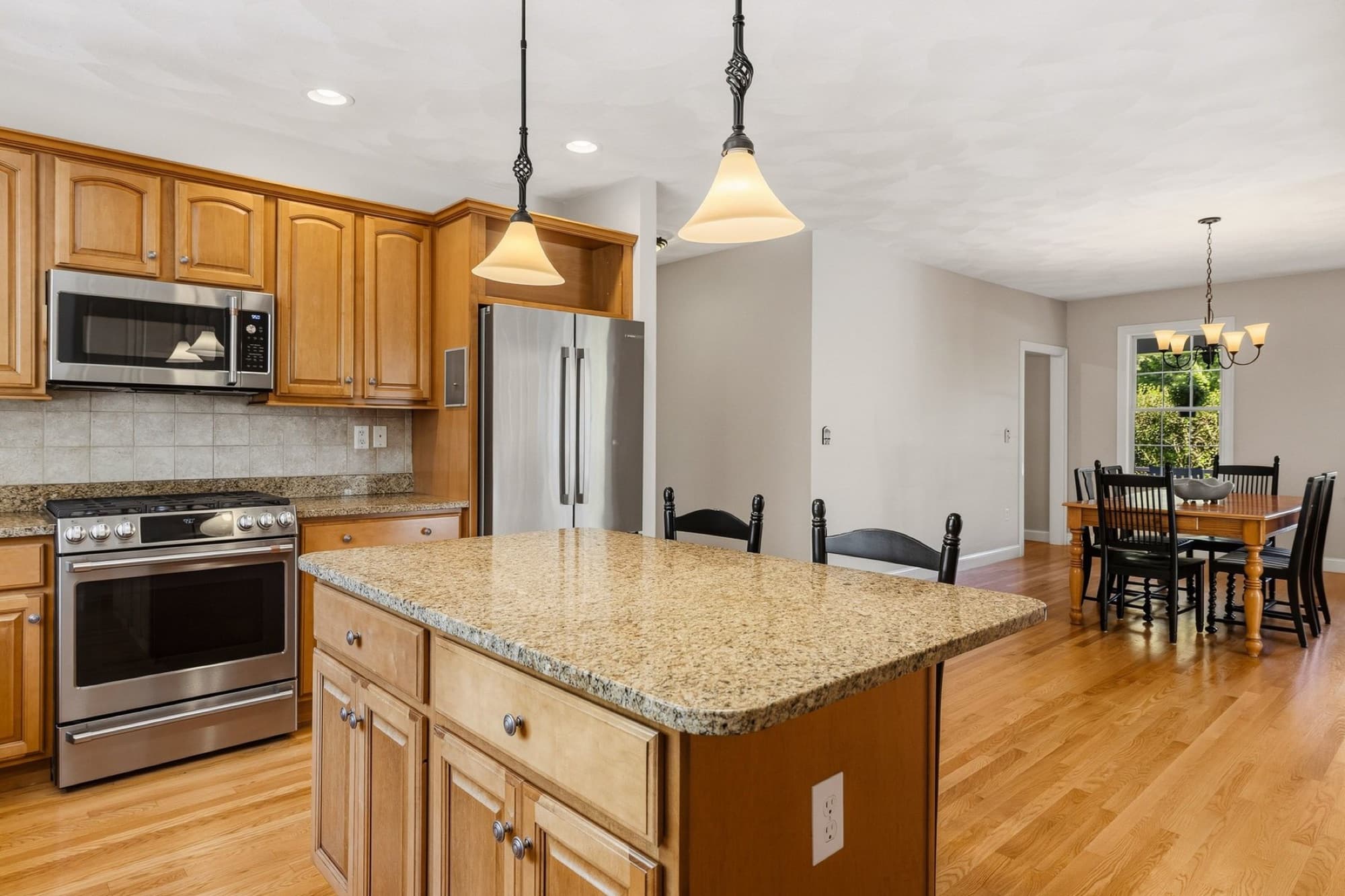 The kitchen island under pendant lights, looking through to the dining room