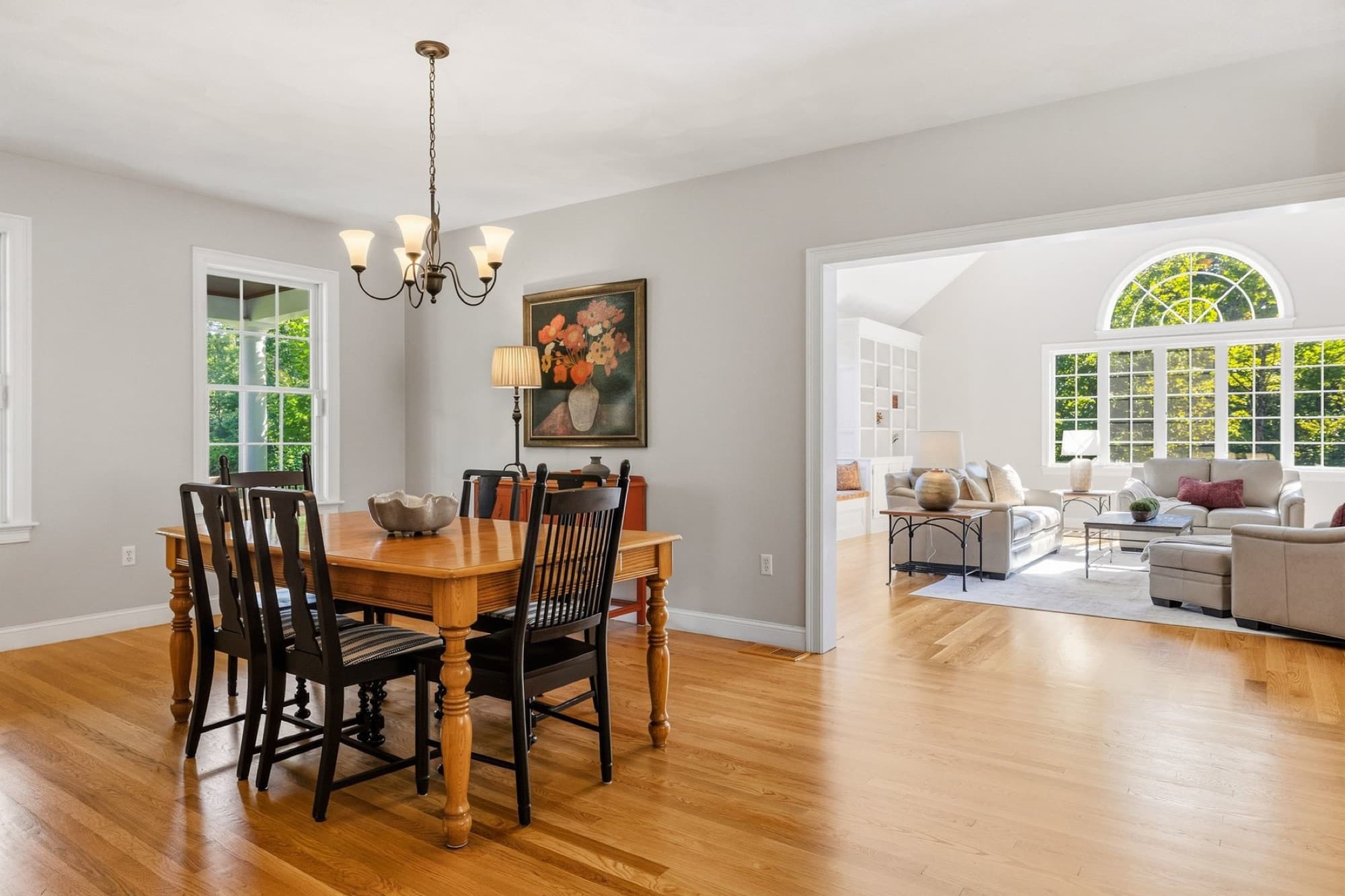 The dining room with a chandelier and 2 windows, open to the family room